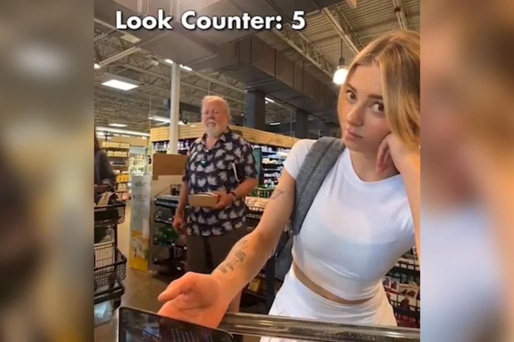 Woman, identified as Antonia Clarke, filming herself at a supermarket self-checkout line with a man looking in her direction