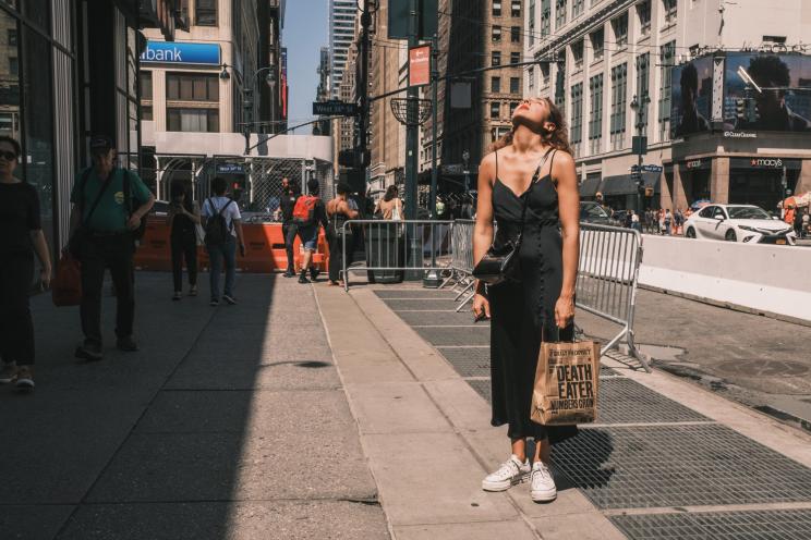 A woman takes a moment to feel the sun on a warm day on 7th avenue by Penn Station in midtown Manhattan