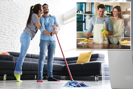 Young couple kissing while man mops the floor during housework chores