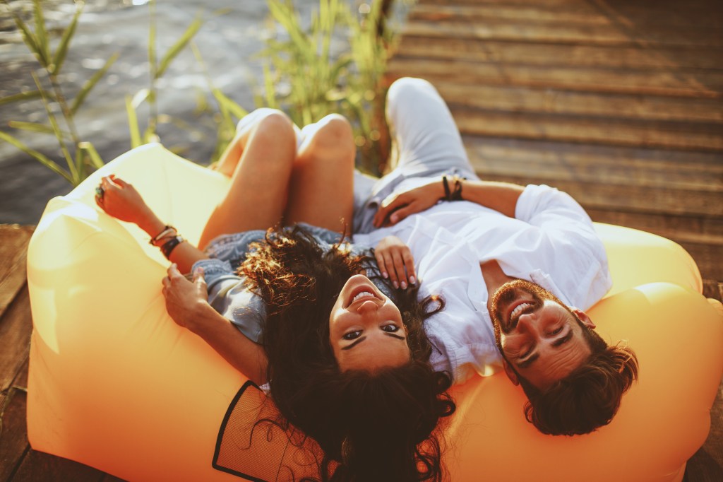 Young couple lying in a lazy bag during the sunset