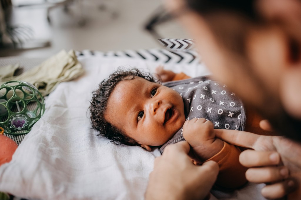 Young couple is playing with their newborn baby at home