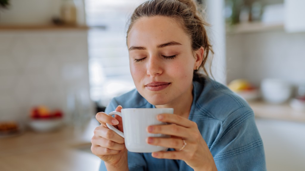 Young woman enjoying cup of coffee at morning, in a kitchen.