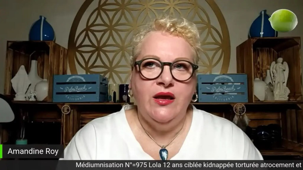 A screenshot of Amandine Roy, a woman wearing glasses and a necklace, from her deleted YouTube video in her online show 'Mediumisation' from December 2021.