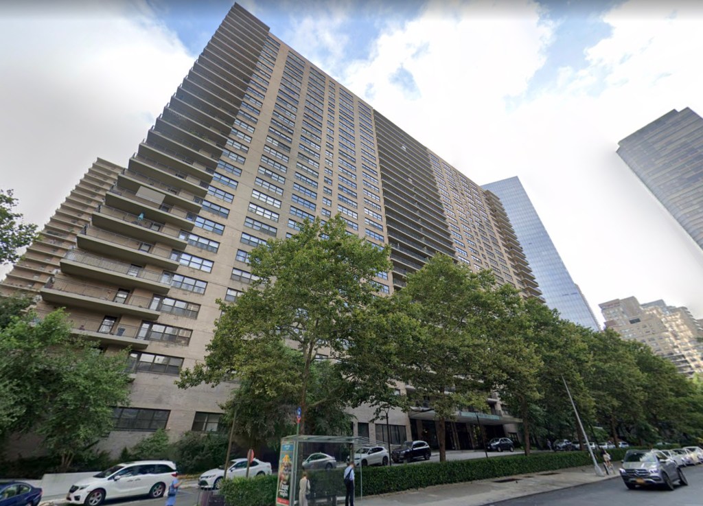 A tall building of Lincoln Towers apartment complex, with trees and parked cars on the side, located on the Upper West Side of Manhattan, New York City