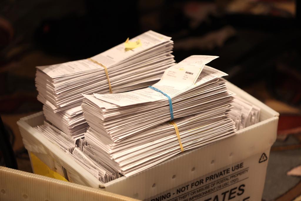 A USPS mail crate holds absentee ballots which are held together with rubber bands. 