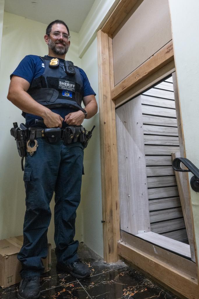 Sheriff Craig McCosker standing next to the hidden doorway to a secret underground room