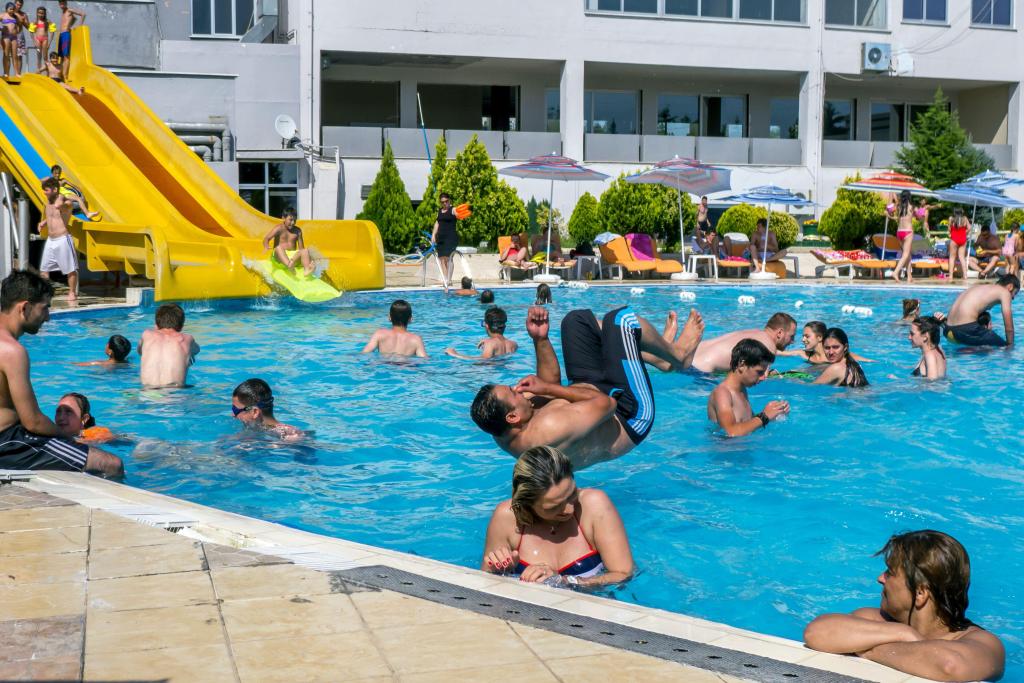 2B57130 People enjoy swimming, jumping and sliding into the public swimming pool at Edirne in northern Turkey on a hot summer day.