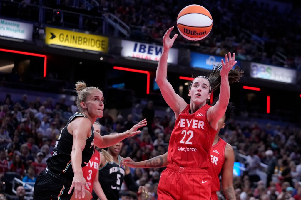 Indiana Fever's Caitlin Clark (22) grabs a rebound ahead of New York Liberty's Leonie Fiebich (13) during the first half of a WNBA basketball game, Saturday, July 6, 2024, in Indianapolis.