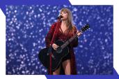 Taylor Swift plays guitar and sings while confetti falls behind her.