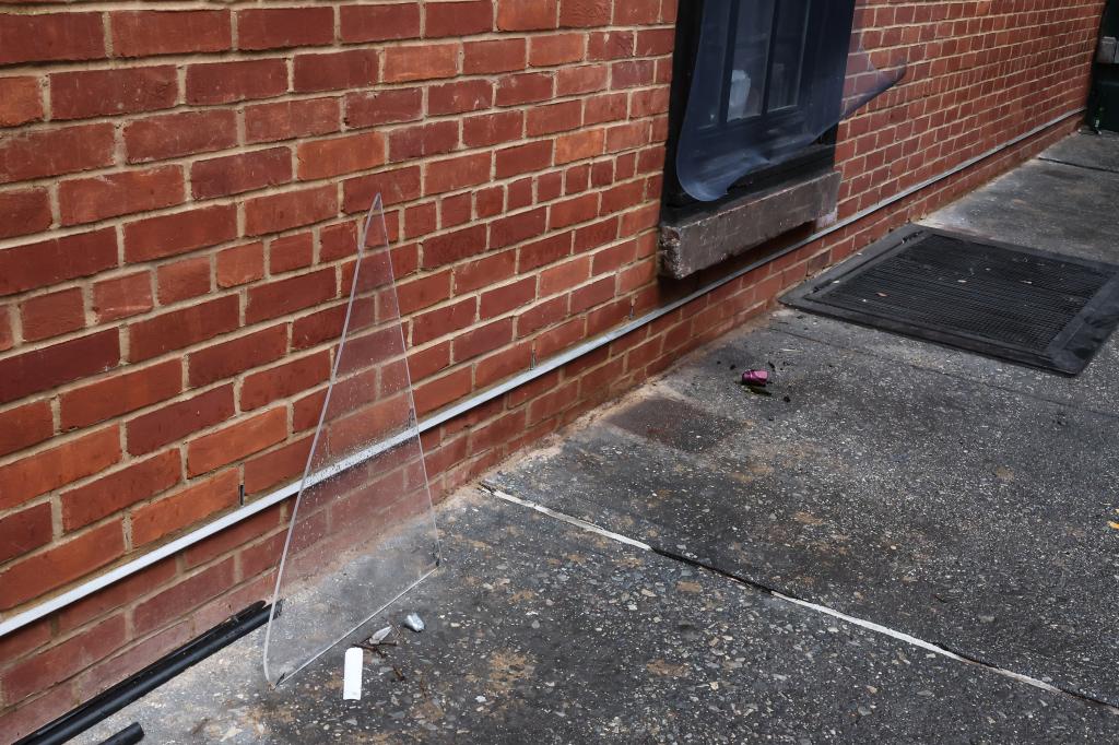 A broken pane of glass on the sidewalk leans against a brick wall outside the Waverly Inn in the W