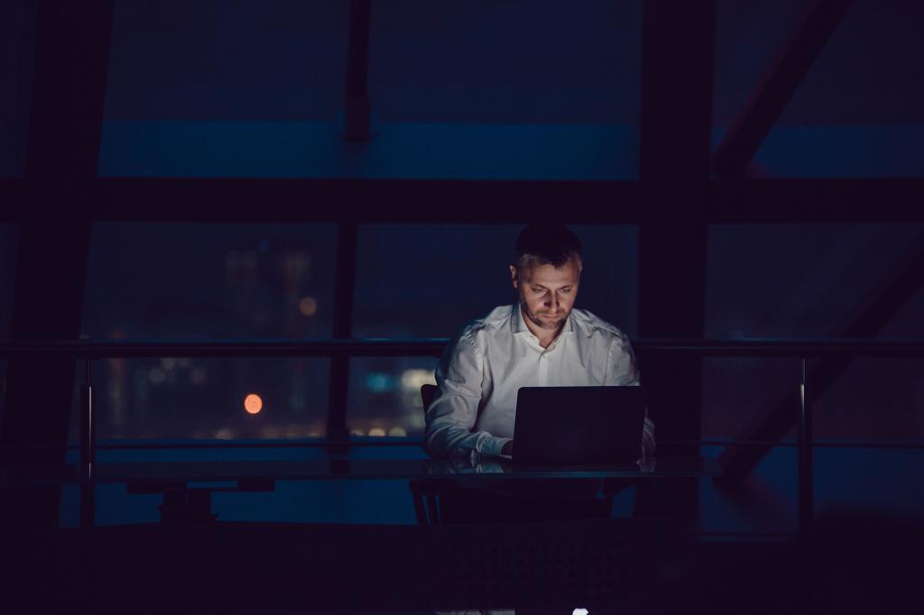 Businessman working on laptop in night office.