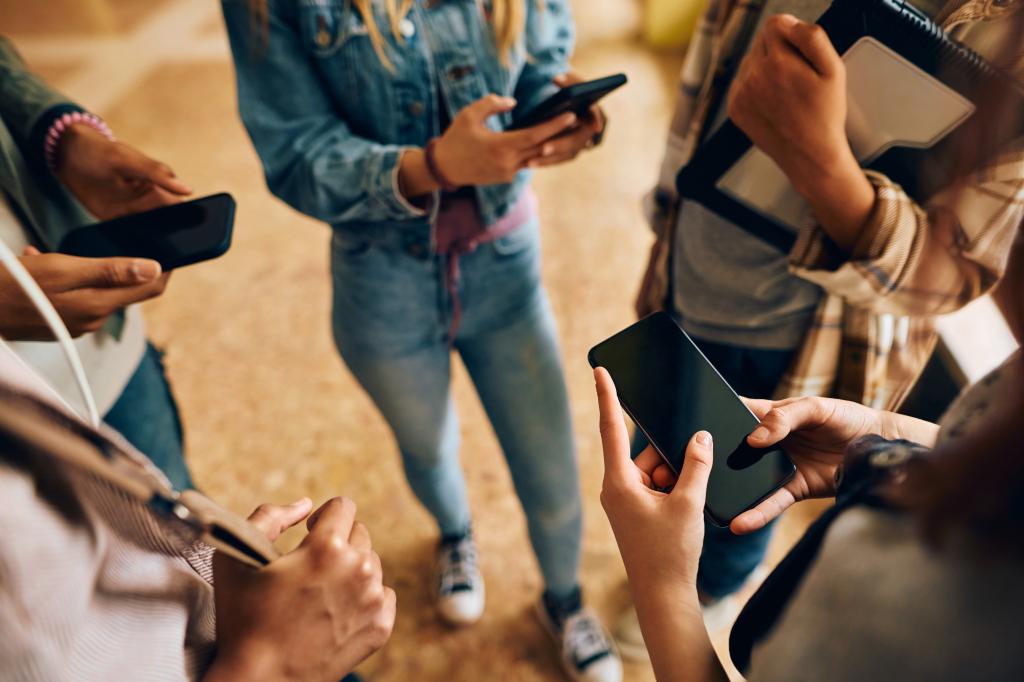 Kids standing with their cell phones. 