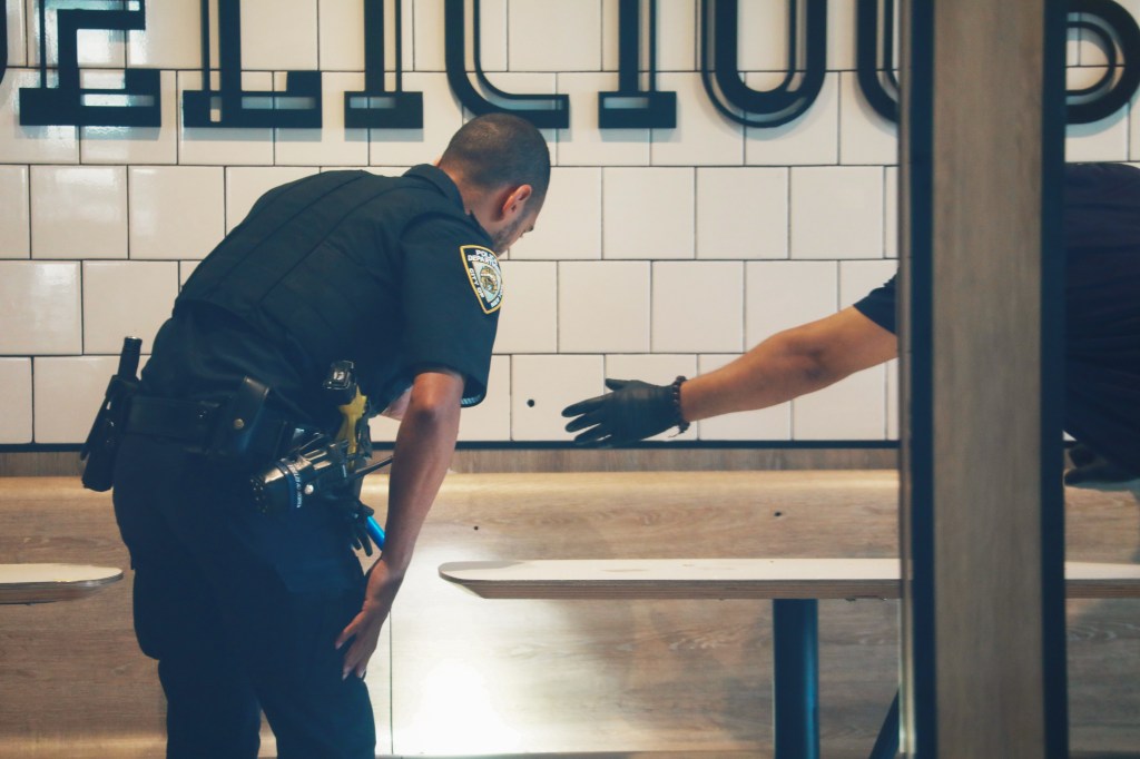 Cops checking evidence, pointing at a bullet hole, inside a Mc Donald Restaurant 