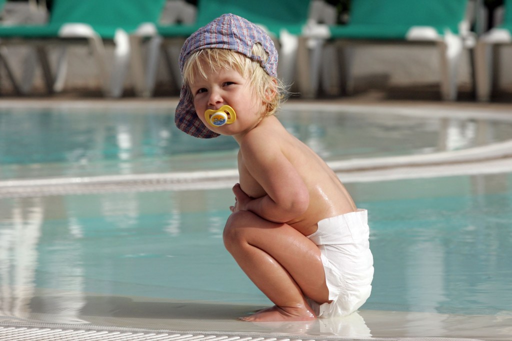 CXE7DK Pajara, an infant in diapers sitting in a swimming pool