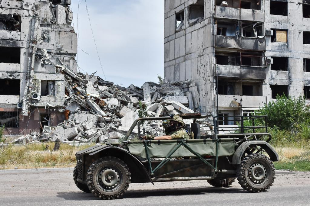 Ukrainian soldiers seen driving in an evacuation buggy near an apartment building heavily damaged by the Russian shelling.