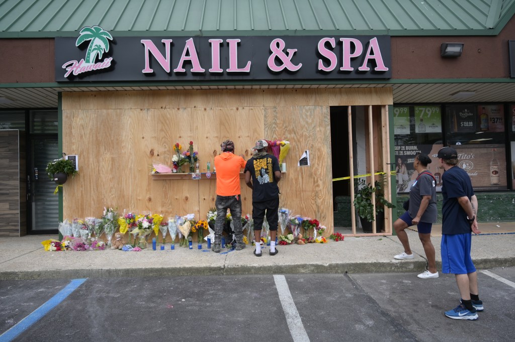 People bringing flowers to the front of a Nail & Spa store, severely damaged by an SUV driven by an alleged drunk driver, resulting in casualties.