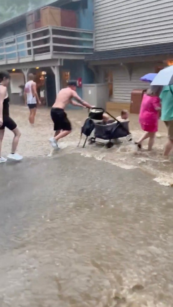 A group of people wading through flooded walkways at Dollywood theme park in Pigeon Forge, Tennessee, after heavy rainfall