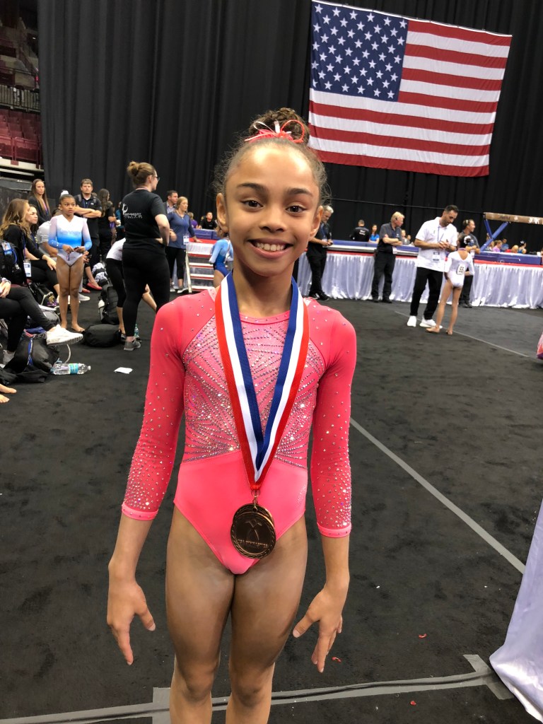 Young gymnast Hezly Rivera in a pink leotard, training at ENA Gymnastics