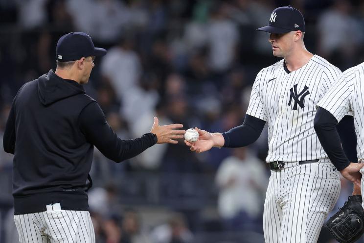 Yankees relief pitcher Clay Holmes (35) hands the ball to manager Aaron Boone (17) after being taken out of the game against the Seattle Mariners during the ninth inning at Yankee Stadium.