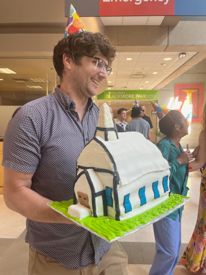 A man smiling carrying a birthday cake. 