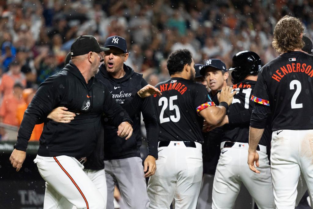 Yankees manager Aaron Boone, second from left, and Baltimore Orioles major league field coordinator/catching instructor Tim Cossins, left, argue after players cleared the benches during the ninth inning of a baseball game, Friday, July 12, 2024.