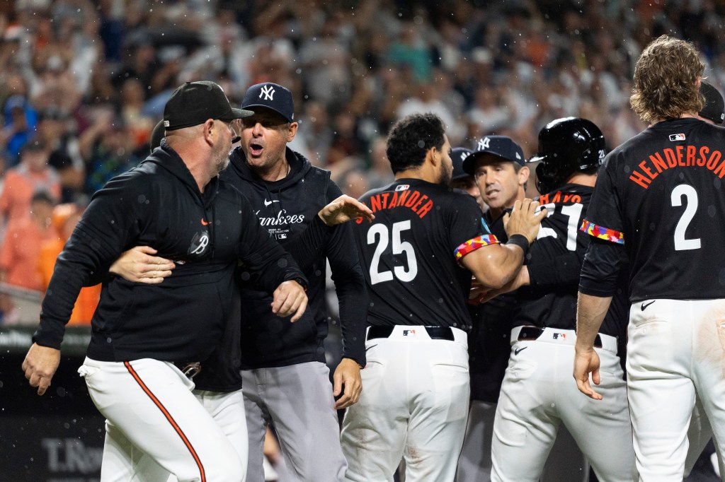 Yankees manager Aaron Boone, second from left, and Baltimore Orioles major league field coordinator/catching instructor Tim Cossins, left, argue after players cleared the benches during the ninth inning of a baseball game, Friday, July 12, 2024.