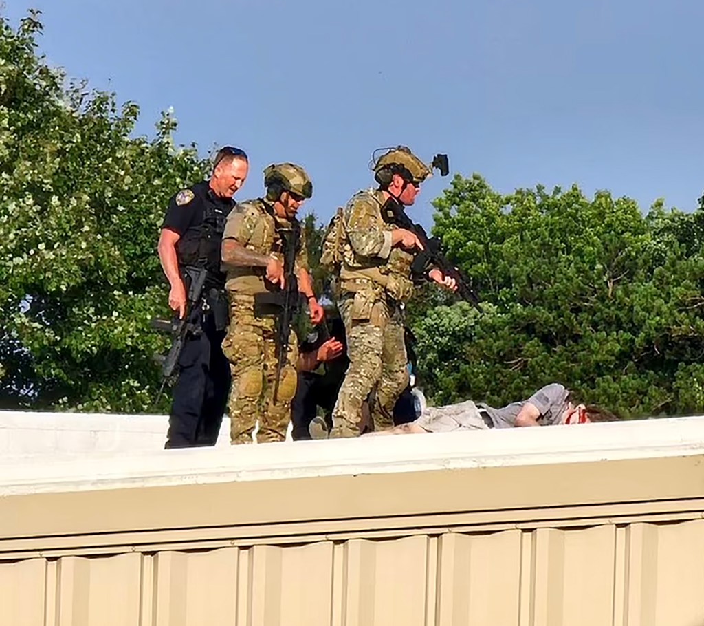 Officers standing over the alleged gunman who shot former President Donald Trump at a Pennsylvania rally on July 13, 2024.