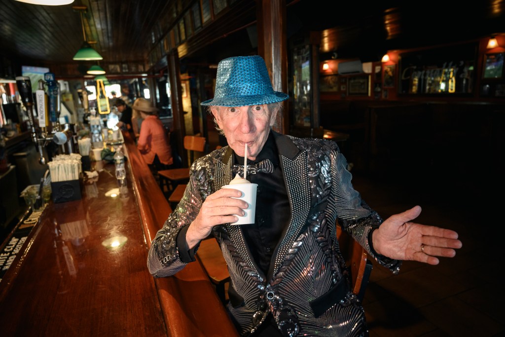 Owen Loof, the best dressed man in Rockaway, wearing a bedazzled blazer and blue hat, sipping a drink at Connolly's bar.