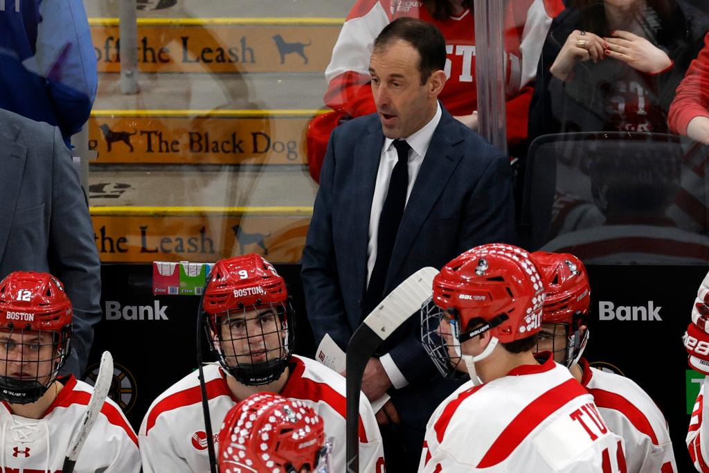 Boston University head coach Jay Pandolfo in a suit, talking strategies to his hockey team during a timeout in the third period at the Beanpot Semifinals game