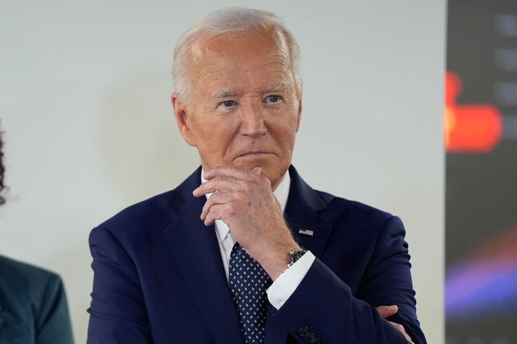 President Joe Biden in a suit, listening attentively during his visit to the D.C. Emergency Operations Center.