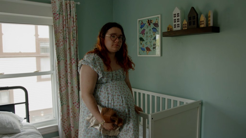 A pregnant Prisha Mosley standing next to a crib.