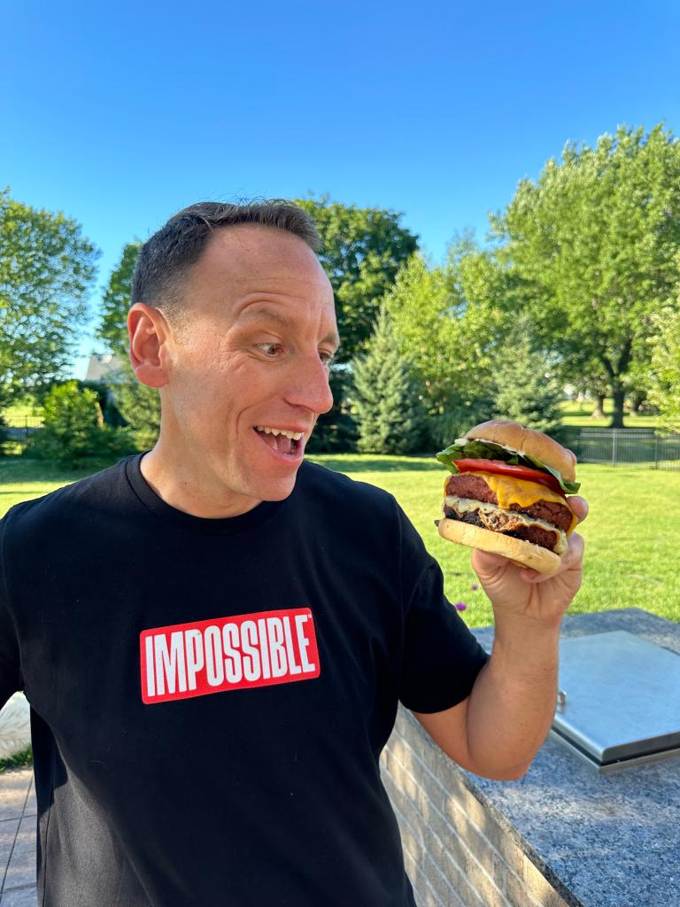 Joey Chestnut, reigning Nathan's hot dog eating champion, holding a burger in association with Impossible Foods