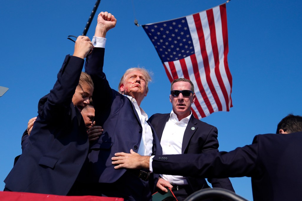 Trump lifts his fist after an apparent assassination attempt.