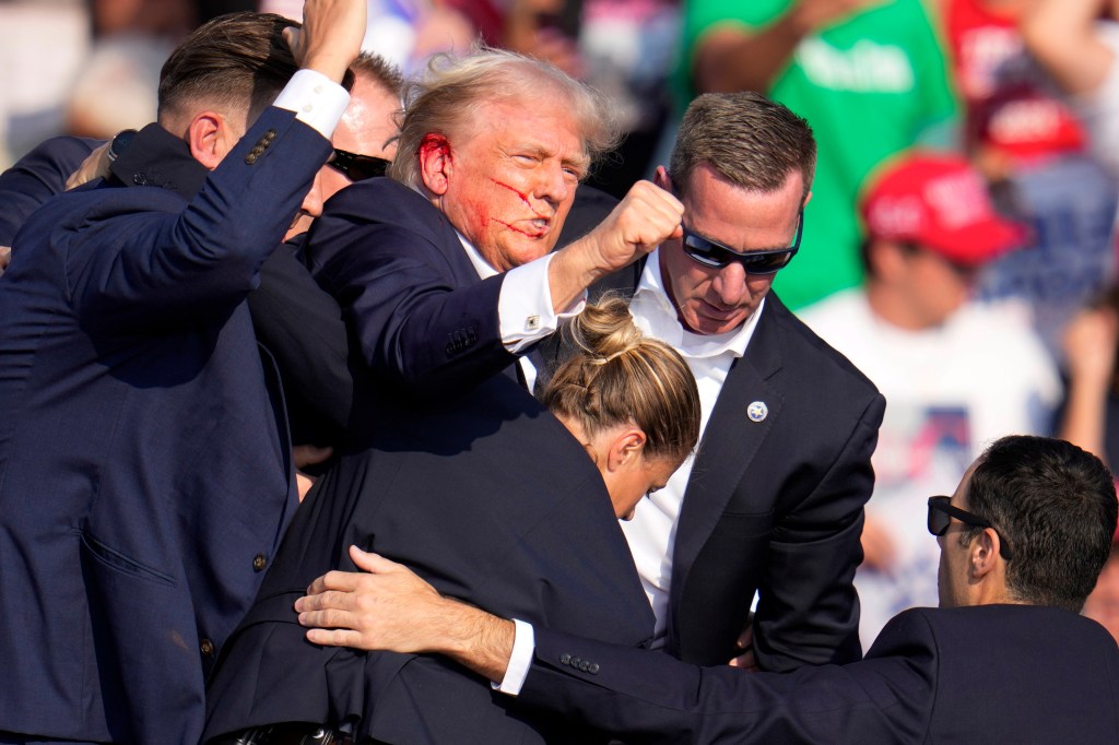 Republican presidential candidate former President Donald Trump is helped off the stage by U.S. Secret Service.