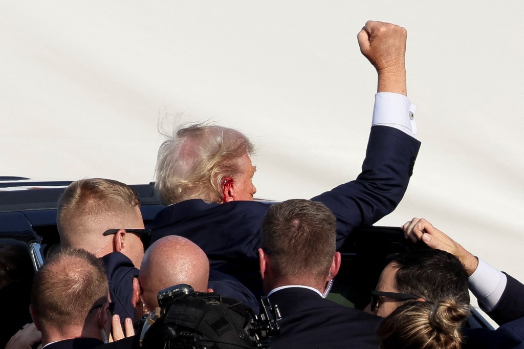 Trump gestures as he is assisted by security personnel after gunfire rang out during a campaign rally at the Butler Farm Show in Butler, Pennsylvania, U.S., July 13, 2024.