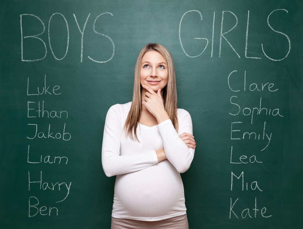 Pregnant woman in front of chalk board with baby names 