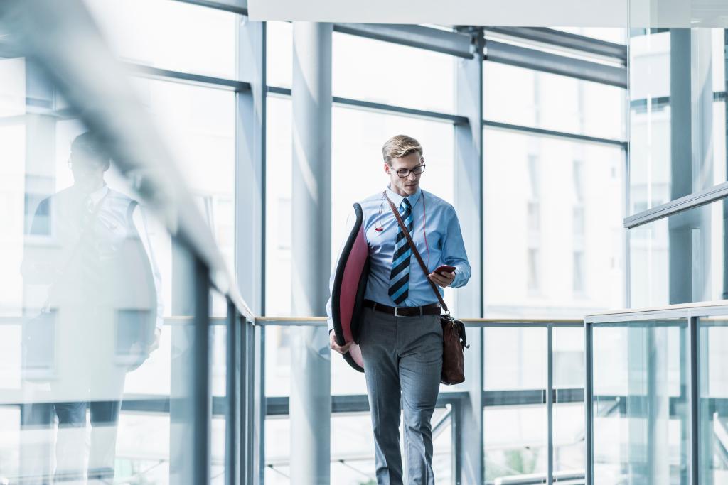 STOCK Businessman with cell phone carrying surfboard in office