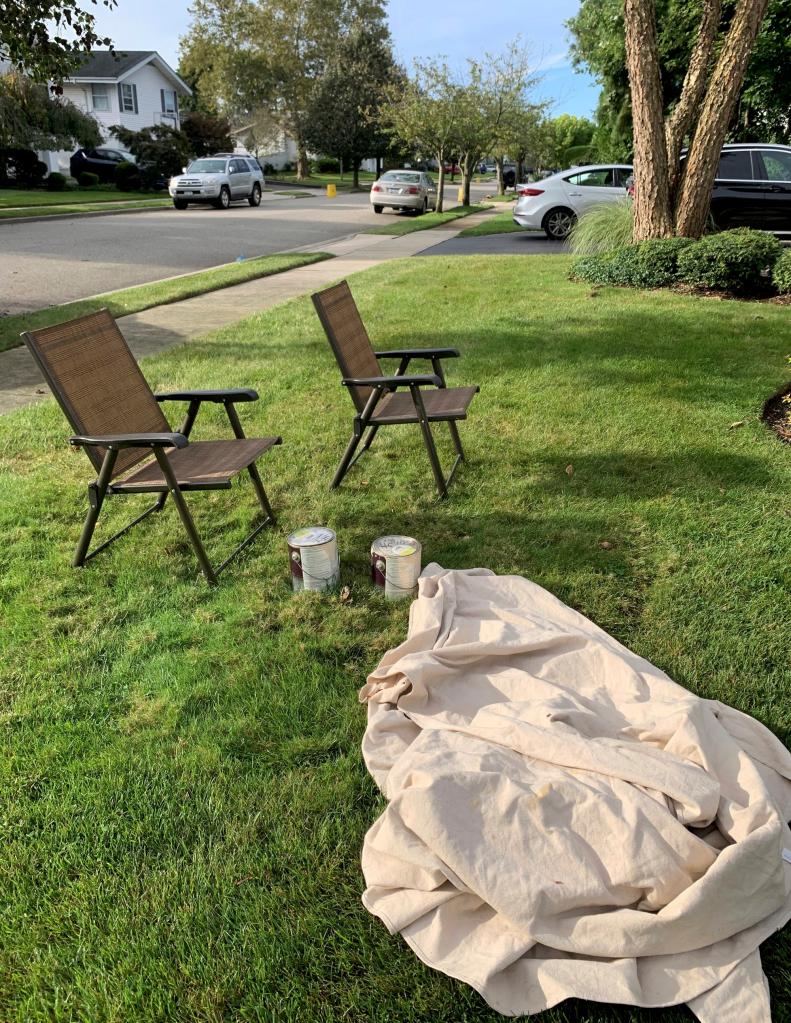 Lawn chairs and paint buckets arranged on the grass in front of a house at 31 Friendly Ln, Jericho, NY