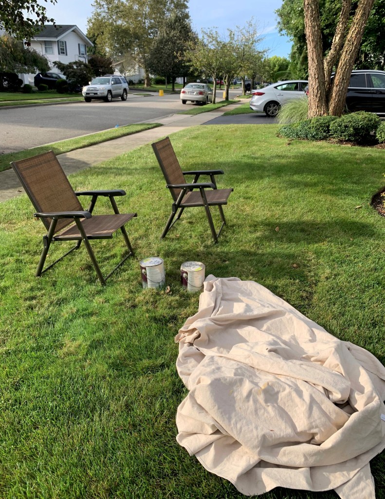 Lawn chairs and paint buckets arranged on the grass in front of a house at 31 Friendly Ln, Jericho, NY