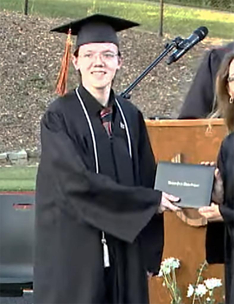 Thomas Matthew Crooks accepts his diploma wearing a black cap and gown.