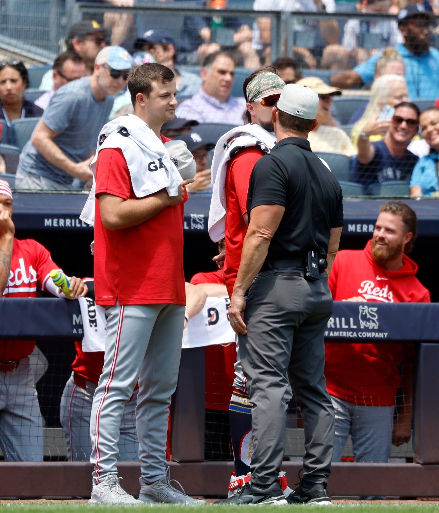 An umpire speaks with a pair of Reds pitchers Graham Ashcraft and Carson Spiers.