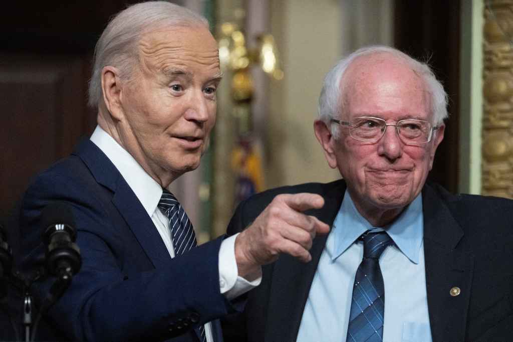 President Joe Biden gestures as Senator Bernie Sanders, Independent from Vermont, looks on during an event about lowering healthcare costs in the Indian Treaty Room of the White House in Washington, DC, on April 3, 2024