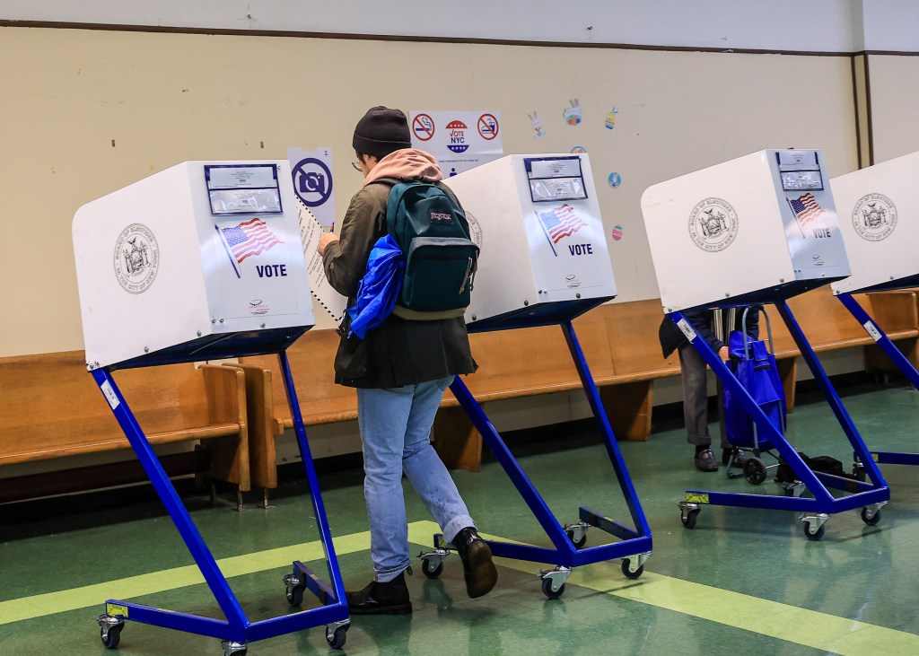 A voter wearing a backpack walks between polling stations on election day. 