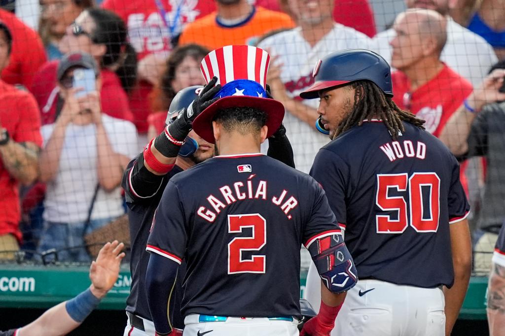 Washington Nationals' Luis Garcia  Jr. gets a celebratory hat after his three-run homer as James Wood looks on during the sixth inning. 