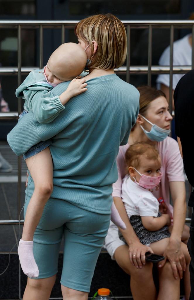 A woman carries a child near Ohmatdyt Children's Hospital that was damaged during Russian missile strikes