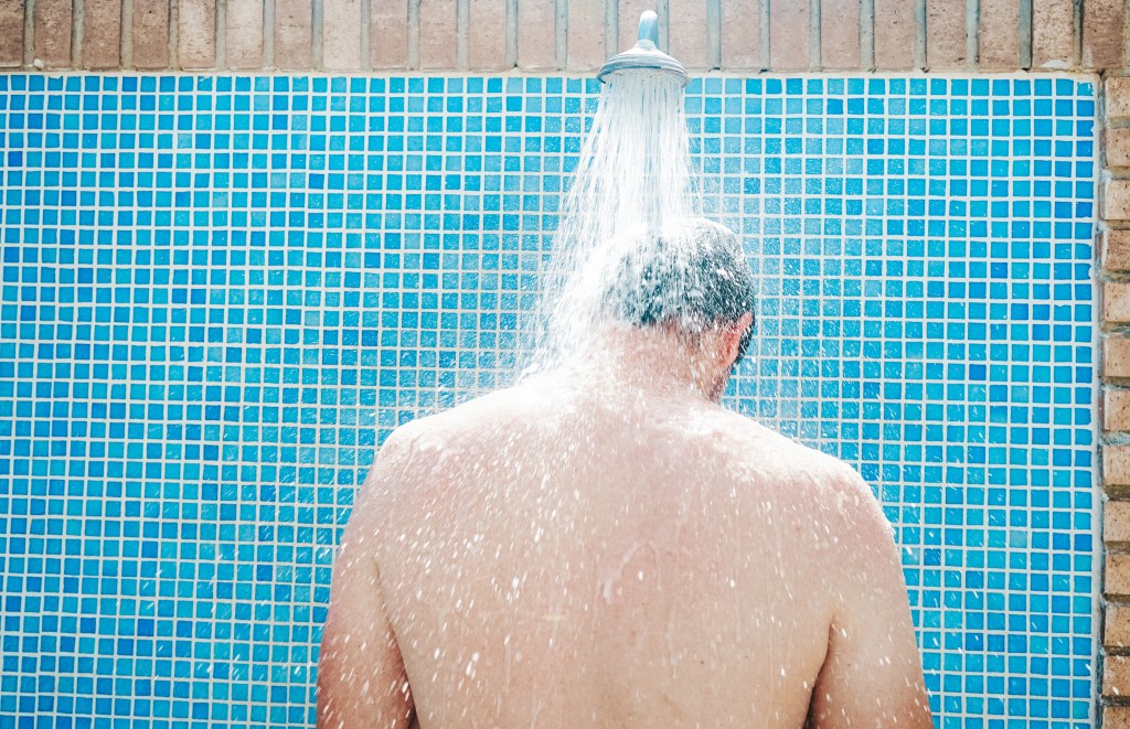 Young man having a shower before pool