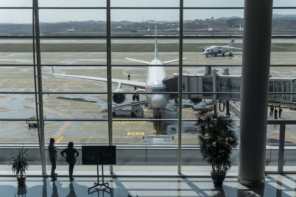 Travellers stand before an Air Koryo aircraft at Pyongyang airport on April 17, 2017