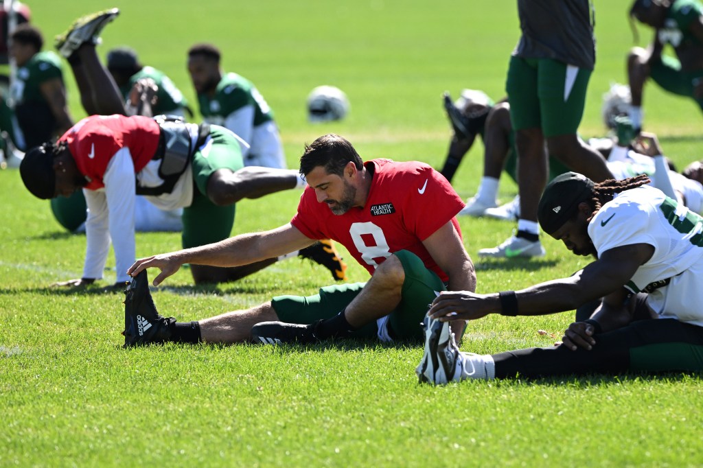 Aaron Rodgers stretches with his Jets' teammates during training camp practice on Aug. 13, 2024.