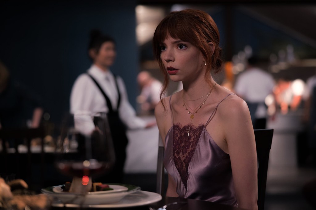 Anya Taylor-Joy sitting at a table in a scene from the 2022 movie 'The Menu'