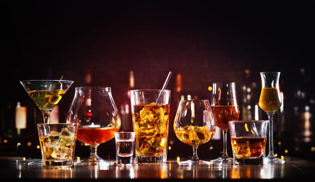 Assortment of various hard alcoholic drinks in glasses displayed on a bar counter